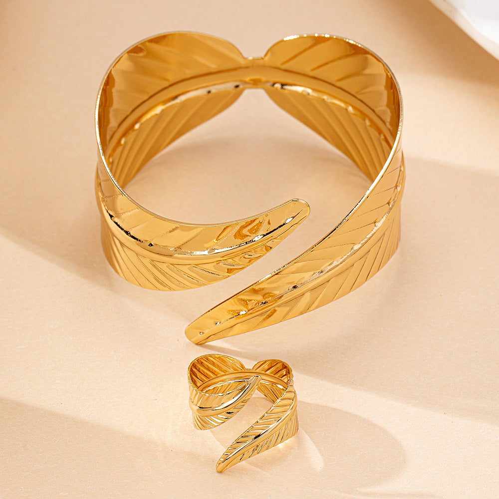 Gold geometric open cuff bracelet and ring set on a beige background