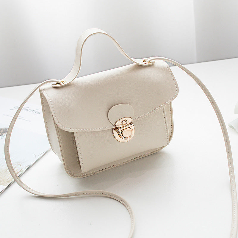 Beige women's mini crossbody bag with a gold clasp on a white surface