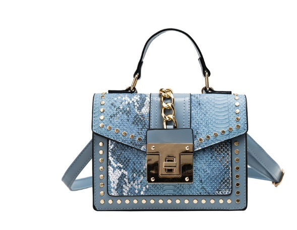 Blue women's crossbody alligator bag with gold accents on a white background