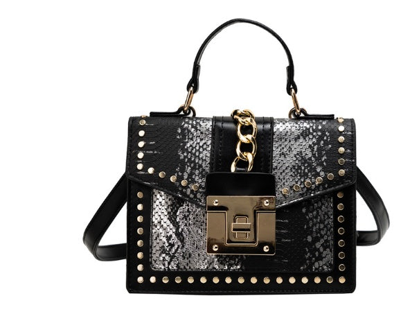 Black women's crossbody alligator bag with gold chain on a white background