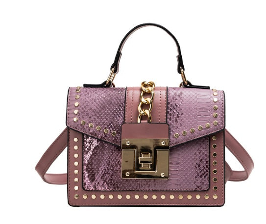Pink women's crossbody alligator bag with gold accents on a white background