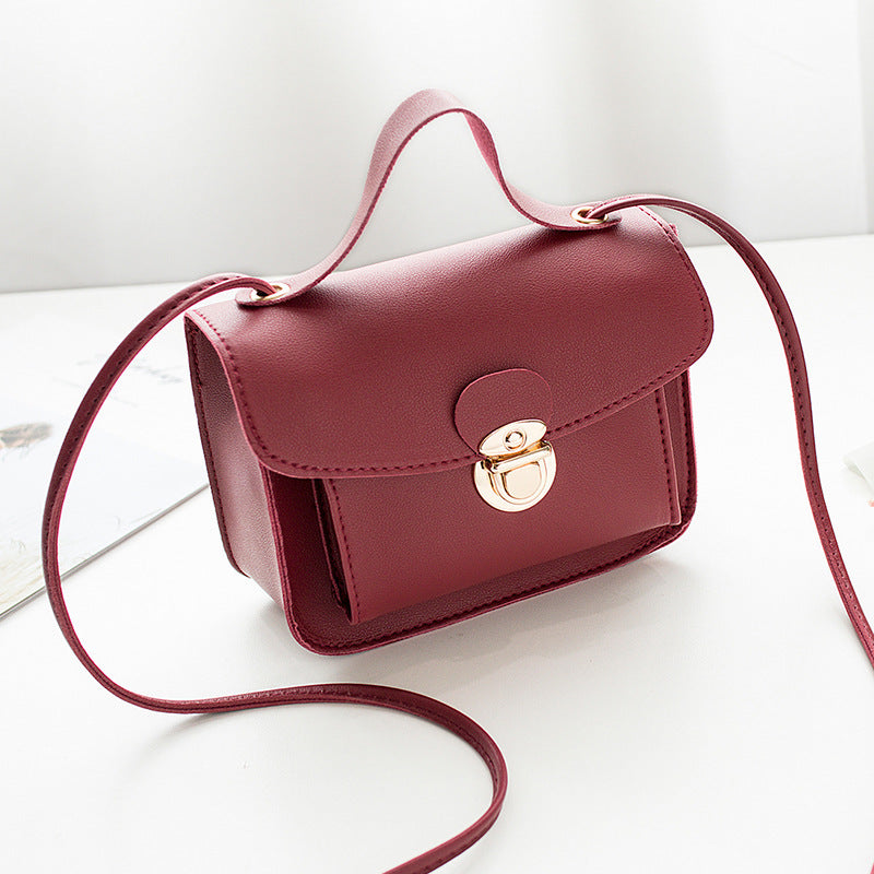 Red women's mini crossbody bag with a gold clasp on a white background