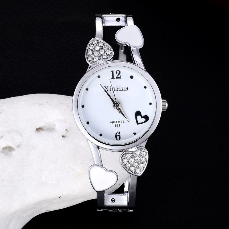 Silver Ladies silver wrist watch with heart designs on a black background