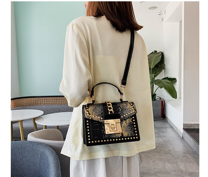 Person wearing a black women's crossbody alligator bag with gold accents