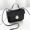 Black women's mini crossbody bag with a gold clasp on a white surface