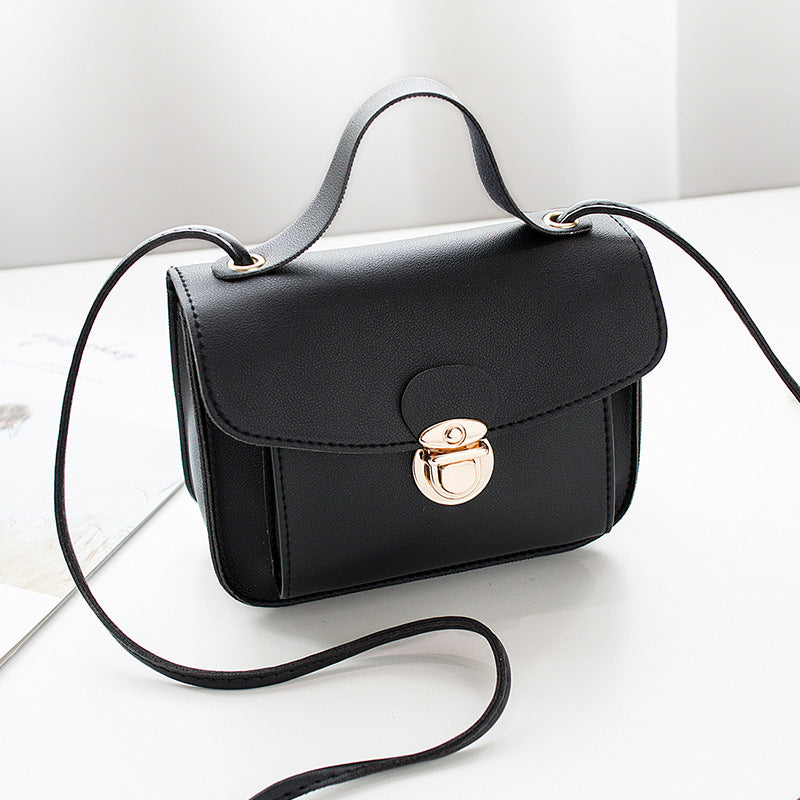 Black women's mini crossbody bag with a gold clasp on a white surface