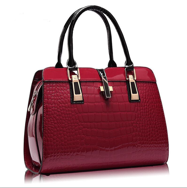 Red crocodile pattern handbag with black handle and gold accents