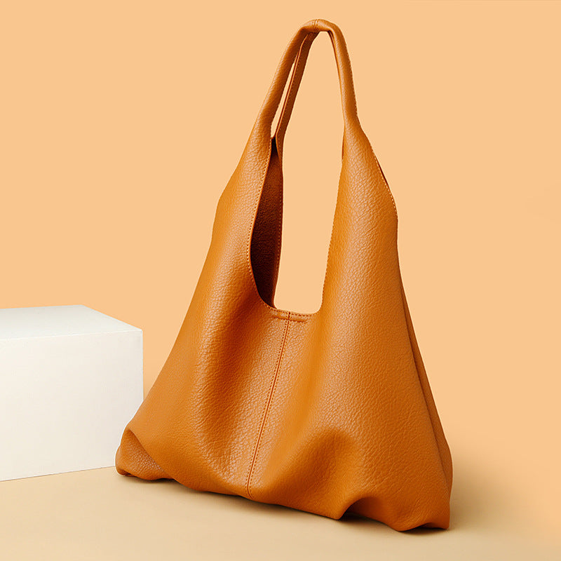 Brown leather underarm shoulder bag on a beige background