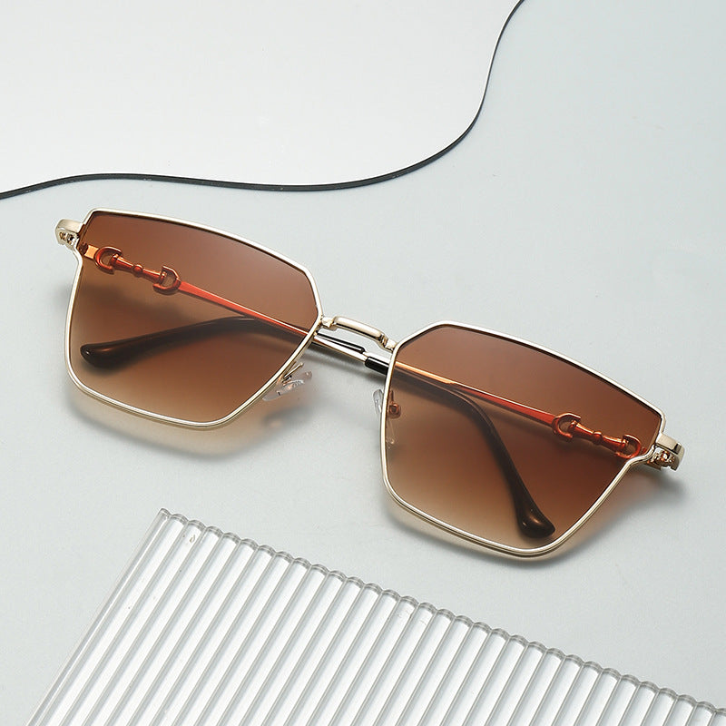 Sunglasses with gold frame and brown lenses on a light gray background