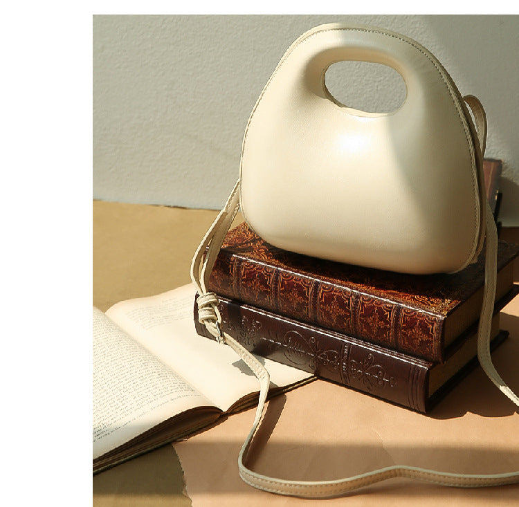 Beige messenger bag with a handle on top of a brown book