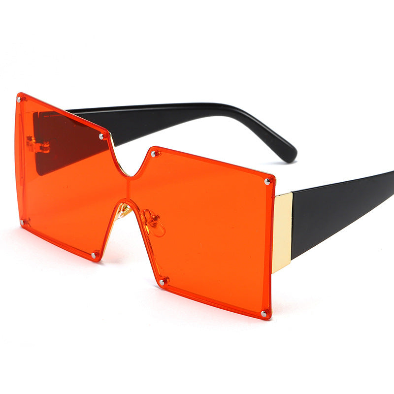 Sunglasses with orange lenses and black and gold frame on a white background