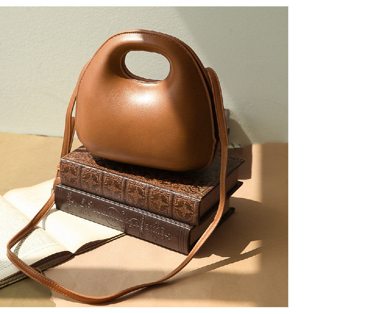 Brown leather messenger bag with embossed design on a light surface