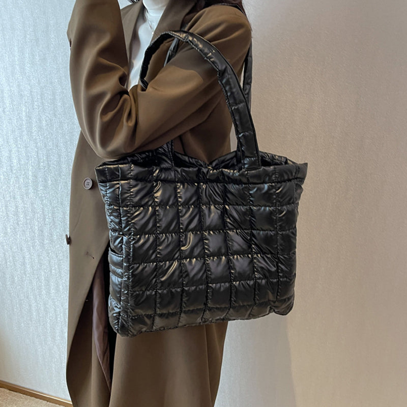 Person holding a black quilted women's plaid shoulder bag