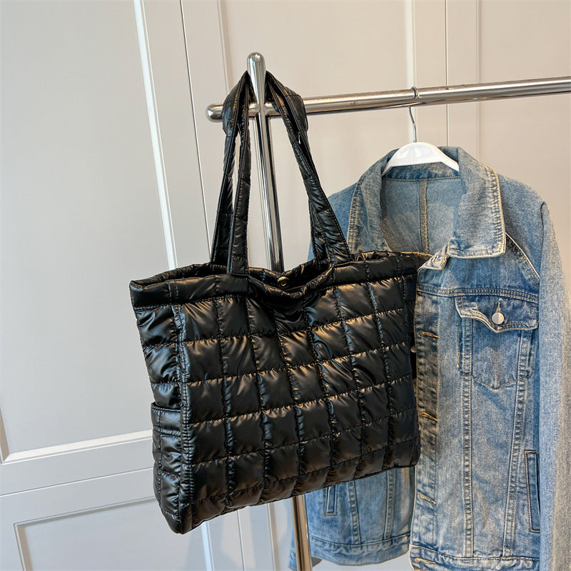 Black quilted women's plaid shoulder bag and denim jacket hanging on a rack