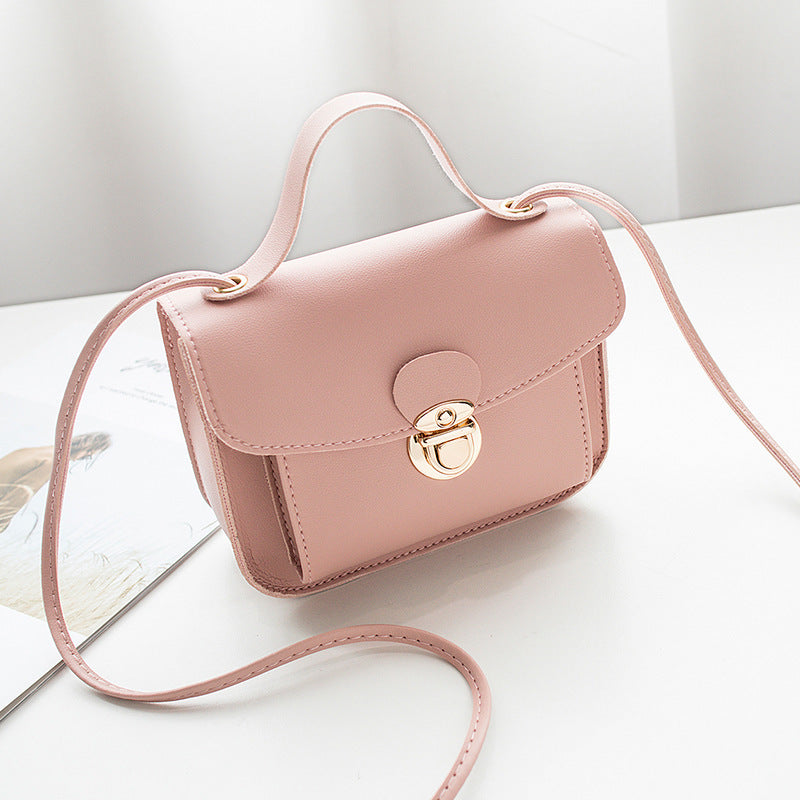 Pink women's mini crossbody bag with a gold clasp on a white surface