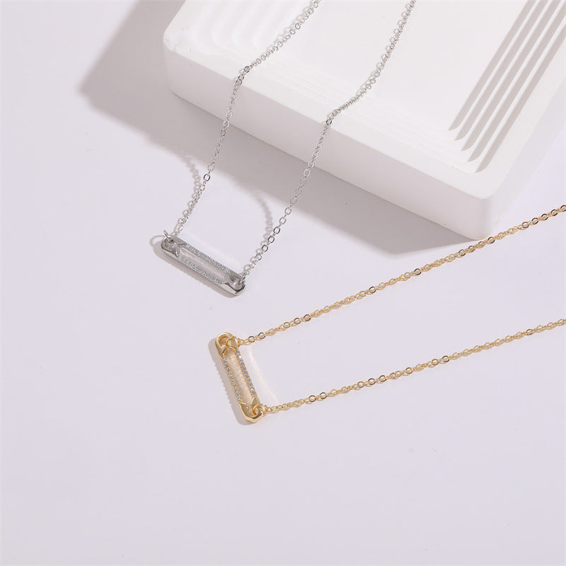 Two pendant necklaces, one gold and one silver, on a light gray background
