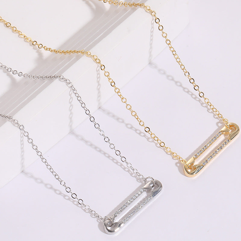 Two zircon pendant necklaces, one gold and one silver, on a light background