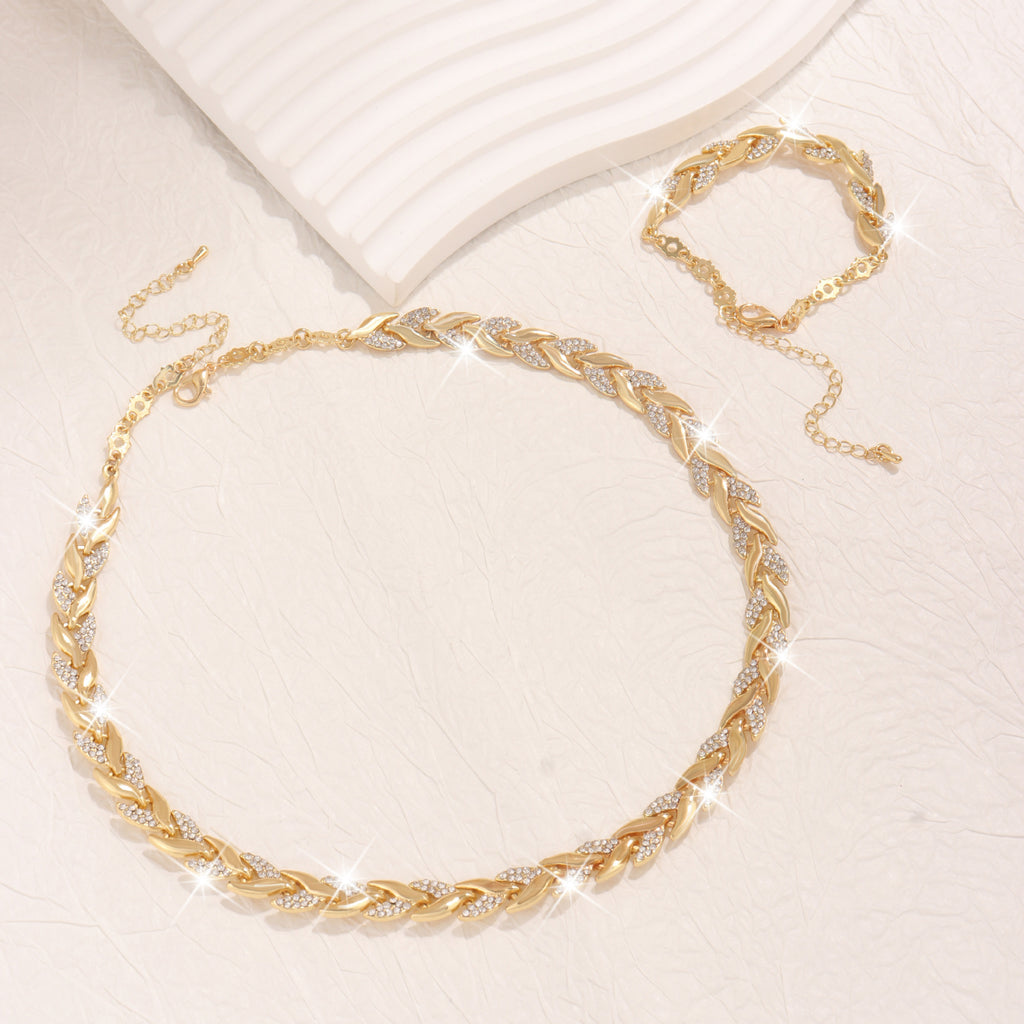 Gold leaf necklace with intricate design on a light beige background