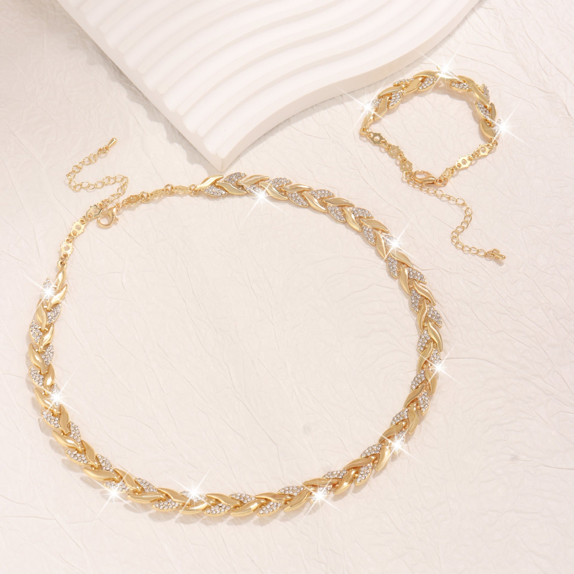 Gold leaf necklace with intricate design on a light beige background
