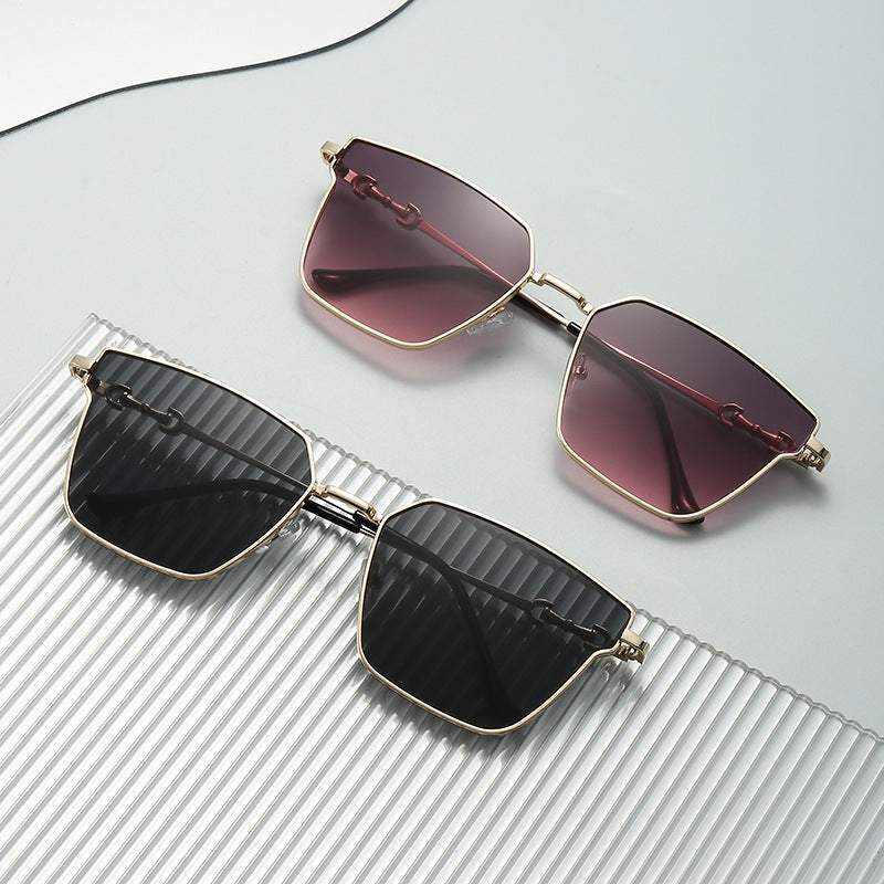 Sunglasses with black and red gradient lenses on a textured surface