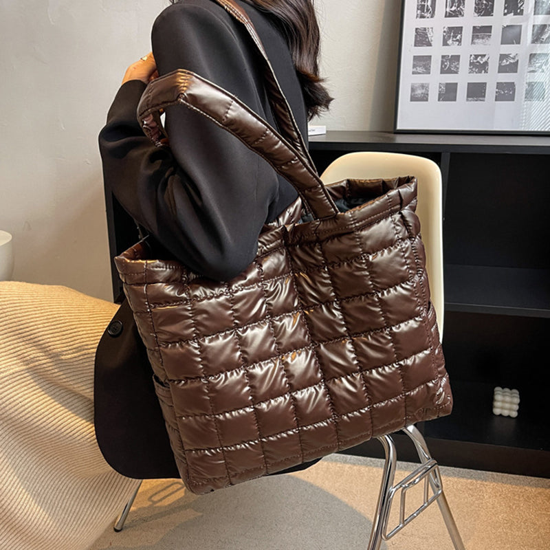 Brown quilted women's plaid shoulder bag held by a person in an indoor setting