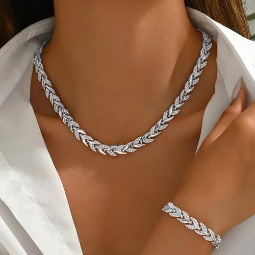 Silver leaf necklace and bracelet on a person wearing a white shirt.