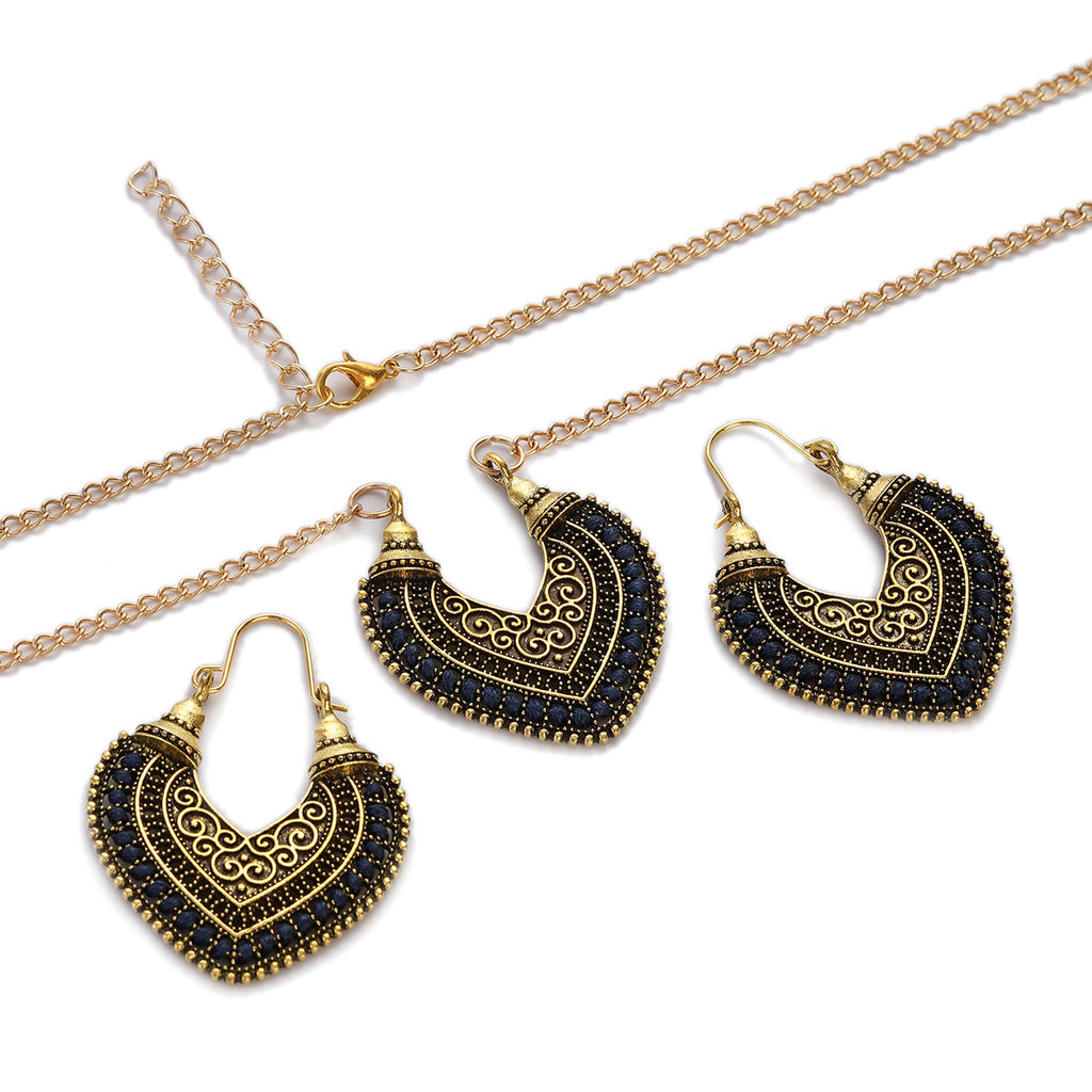Jewelry set with gold and black heart-shaped earrings and necklace on a white background