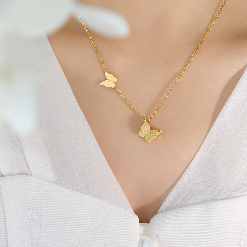 Gold butterfly necklace on a person wearing a white top