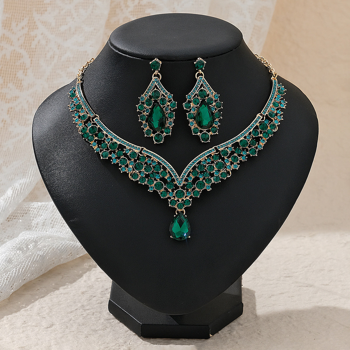 Green gemstone pearl necklace and earrings on a black stand