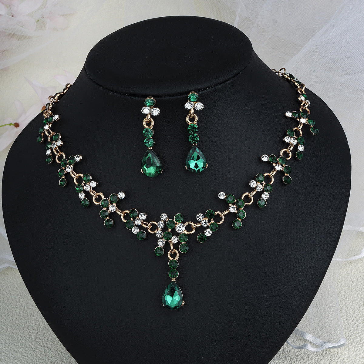 Green pearl necklace jewelry set with earrings on a black mannequin bust.