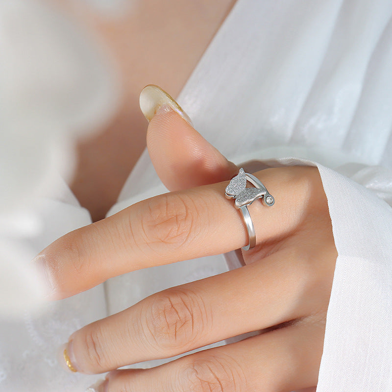 Silver butterfly ring with a heart and arrow design on a person's finger