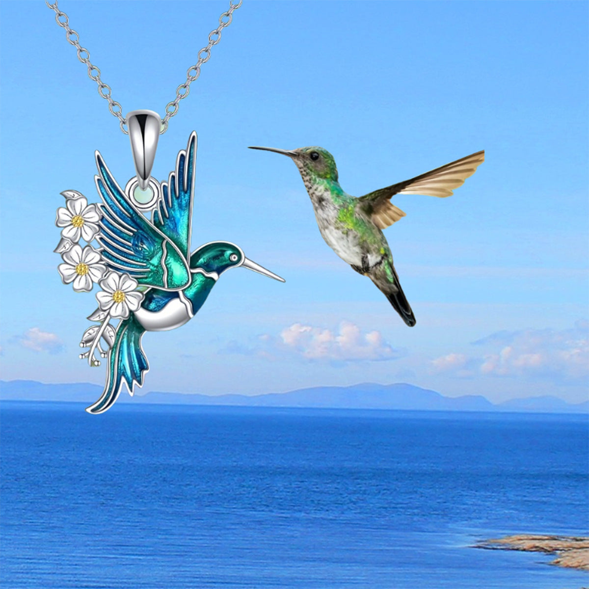 Hummingbird necklace with floral design against a blue sky and ocean background