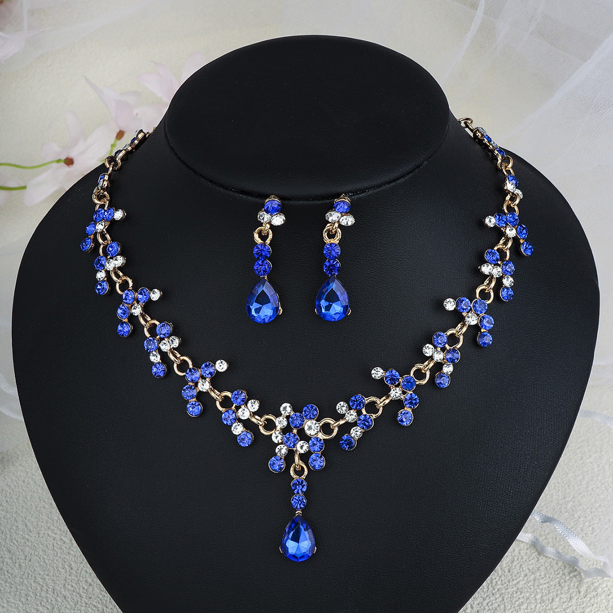 pearl necklace jewelry set with blue and clear stones on a black mannequin bust.