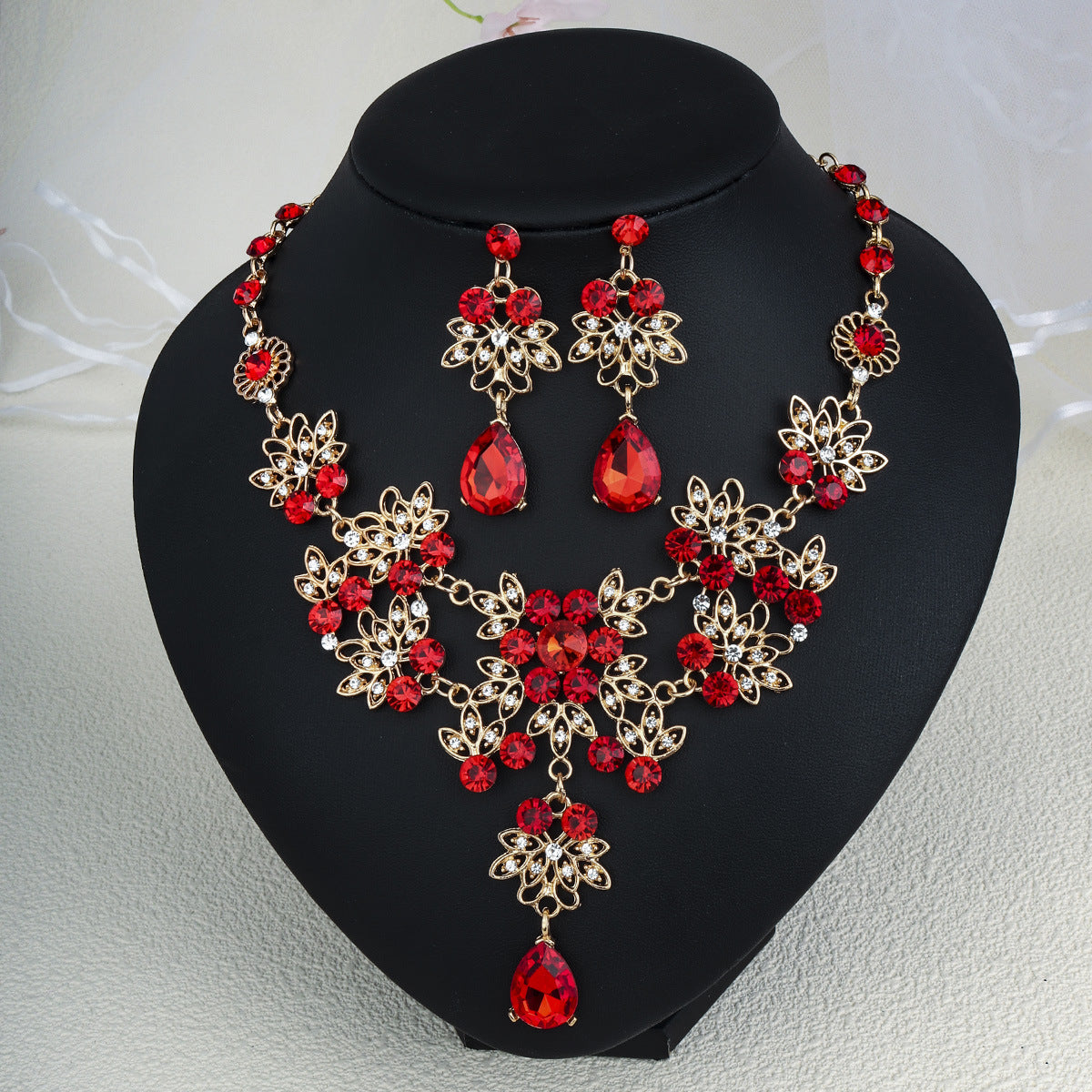 pearl necklace set with red gemstones and gold accents on a black stand.