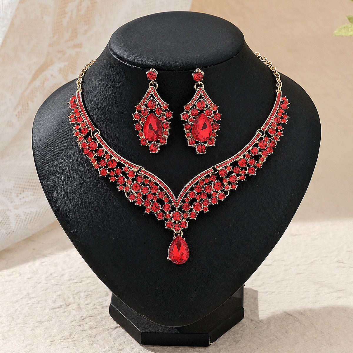 Red gemstone pearl necklace and earrings on a black mannequin bust.