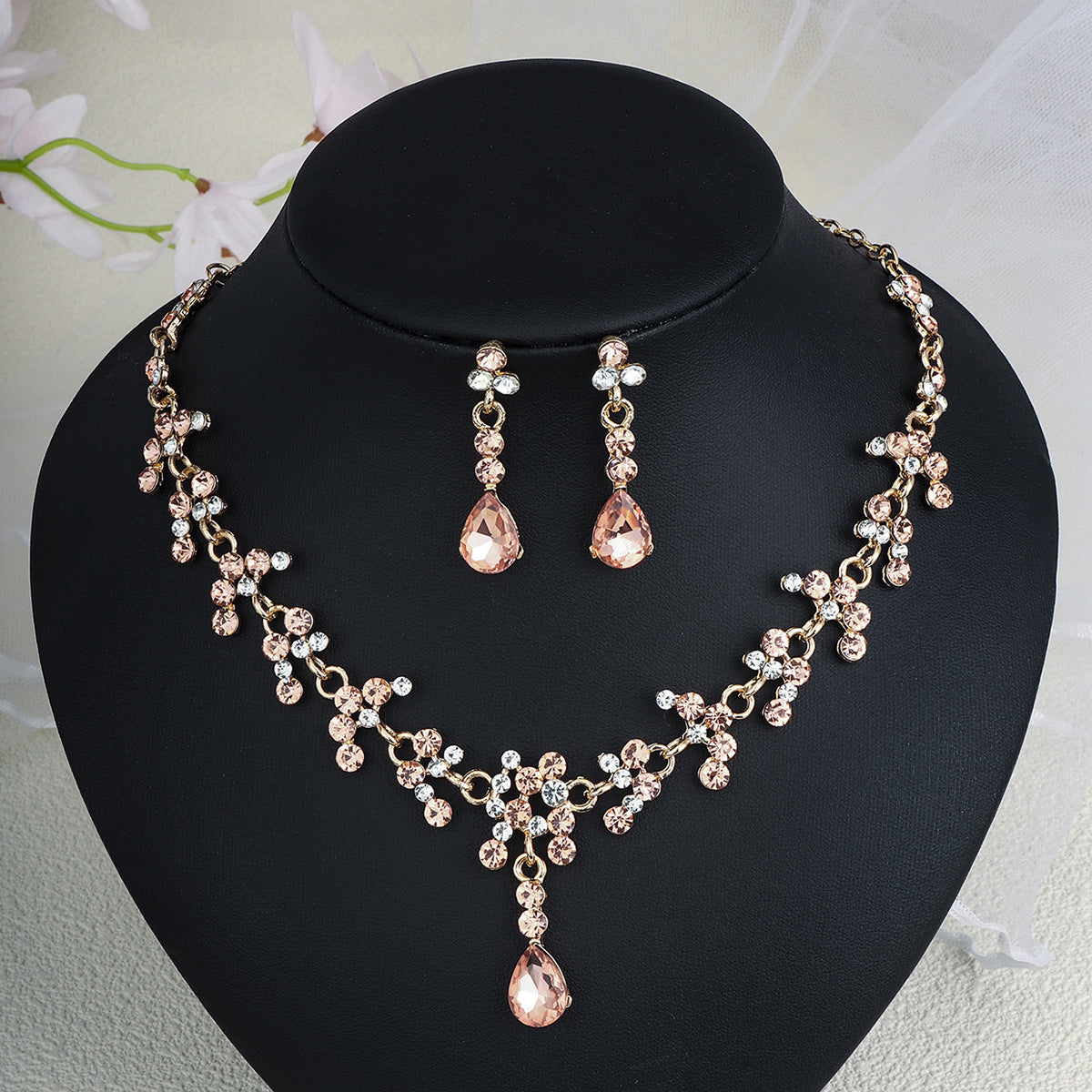 Rose gold pearl necklace and earrings set on a black mannequin bust