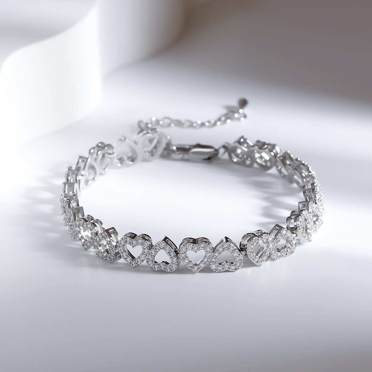 Silver heart bracelet with gemstones on a white background