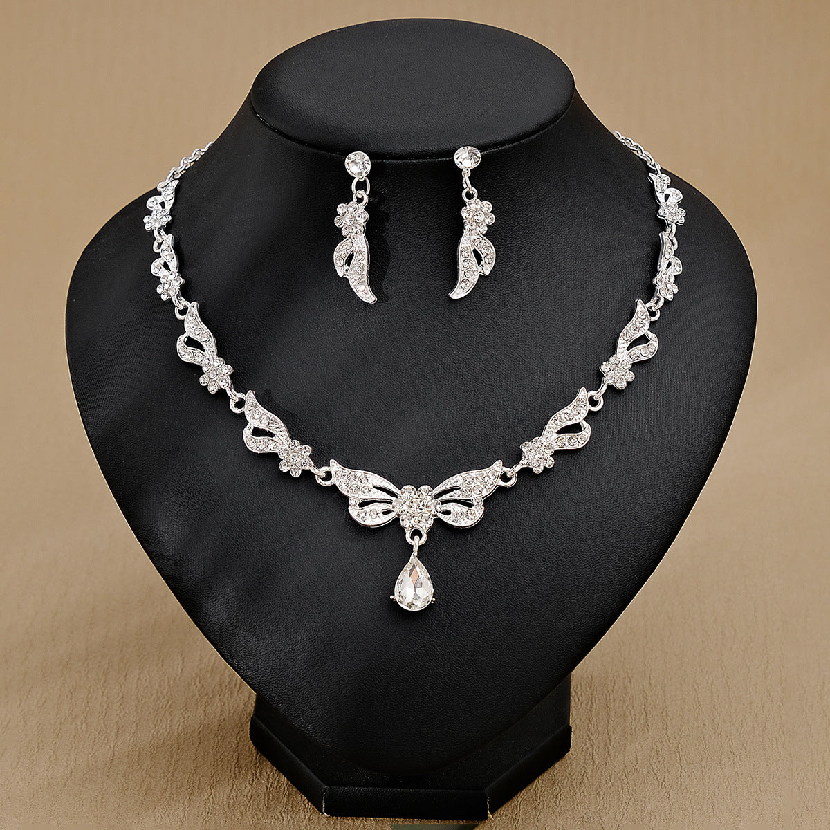 Silver pearl necklace and earrings set against a beige background