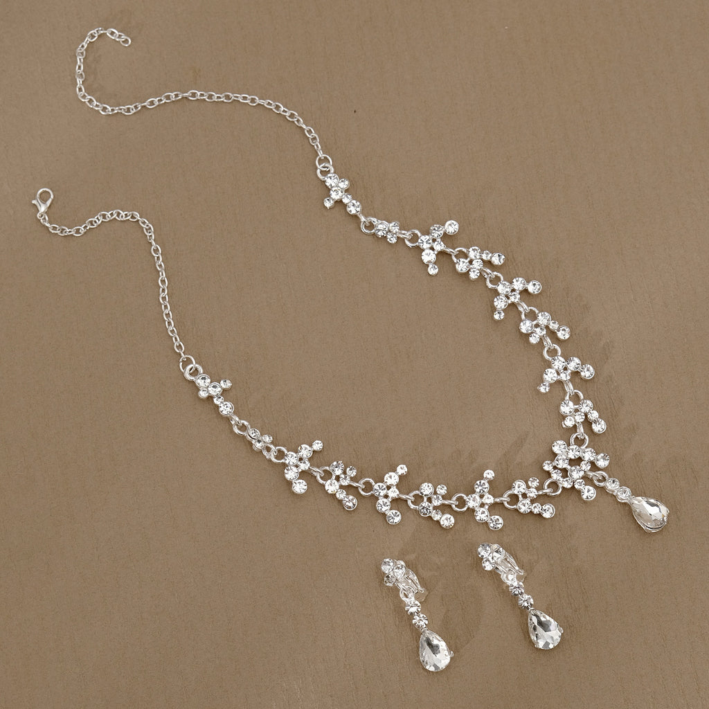 Silver pearl necklace and earrings set on a brown background